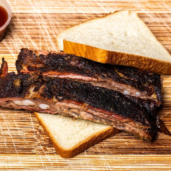 Hot Spot Barbecue ribs with a dark, crispy bark, served on white bread slices.
