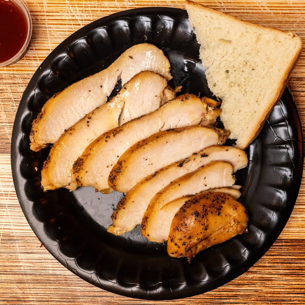 Hot Spot Barbecue's sliced smoked turkey breast with a side of white bread and barbecue sauce.